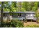 Back of a house with a back deck surrounded by green trees at 6235 Akins Way, Cumming, GA 30041