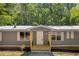 Charming single-story home with gray siding, white trim, metal roof and a covered front porch at 6235 Akins Way, Cumming, GA 30041