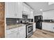 Well-lit kitchen featuring white cabinets, granite countertops, and stainless steel appliances at 6235 Akins Way, Cumming, GA 30041