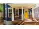 Front porch featuring wooden deck, a yellow front door, navy siding, white trim and support beams at 1454 Rome Nw Dr, Atlanta, GA 30314