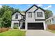 Two story home featuring a two-car garage, black trim, and manicured front lawn at 2111 Nelms Pointe Lndg, Lawrenceville, GA 30043