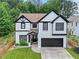Two story home featuring a two-car garage, black trim, and manicured front lawn at 2111 Nelms Pointe Lndg, Lawrenceville, GA 30043