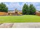 Backyard showcasing a manicured lawn, play set, swing set and lush green trees at 2490 Tack Hill Ct, Dacula, GA 30019