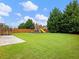Spacious backyard featuring green lawn, tall trees, a swing set and a trampoline at 2490 Tack Hill Ct, Dacula, GA 30019
