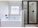 Modern bathroom with a glass-door shower and a soaking tub by a frosted window, bringing natural light at 2490 Tack Hill Ct, Dacula, GA 30019