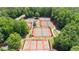 An aerial view shows multiple pristine tennis courts surrounded by mature trees at 3902 Butterstream Way, Kennesaw, GA 30144