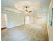 Carpeted primary bedroom with tray ceiling, ceiling fan, neutral walls and access to en-suite bathroom at 1540 Ox Bridge Ct, Lawrenceville, GA 30043