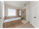 Bright bathroom features a bathtub, tiled floors, a shower, and double doors with an ensuite at 2100 Willshire Gln, Alpharetta, GA 30009