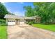 View of the home and garage with a large driveway and lawn with mature trees offering ample parking space at 486 Buttercup Trl, Lawrenceville, GA 30046