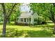 Exterior view displaying a charming home with a front porch, lush lawn, and mature trees at 1730 Lee Peters Rd, Loganville, GA 30052