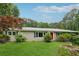 Charming one-story home featuring a manicured lawn, mature trees, and a welcoming red front door at 1926 Parkwood Rd, Snellville, GA 30078