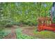 Landscaped backyard featuring a lush lawn, mature trees, planting beds, and a two-story deck at 2715 Braemore Gln, Powder Springs, GA 30127