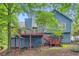 Back exterior featuring blue siding, a two-story deck, mature trees, and a landscaped backyard at 2715 Braemore Gln, Powder Springs, GA 30127