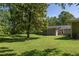 View of the home's exterior and expansive backyard with lush lawn and mature trees at 762 Rockbridge Nw Rd, Lilburn, GA 30047