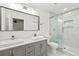 Modern bathroom with double sink vanity, marble tile floors, and a glass-enclosed shower with shower niche at 762 Rockbridge Nw Rd, Lilburn, GA 30047