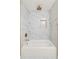 Modern white bathtub featuring marble tile backsplash and gold fixtures in updated bathroom at 762 Rockbridge Nw Rd, Lilburn, GA 30047