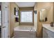 Relaxing bathroom featuring a large bathtub with jets, a vanity with sink, and a window for natural light at 1047 Taso Trl, Acworth, GA 30101