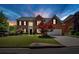 Brick two-story home with manicured lawn, mature trees, and an attached two-car garage on a beautiful lot at dusk at 2372 Oberon Se Walk, Smyrna, GA 30080