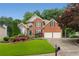 Charming two-story brick home with a well-manicured lawn, a two-car garage, and mature trees at 2026 Cresthaven Walk, Woodstock, GA 30189