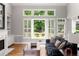 Cozy living room with hardwood floors, a fireplace, built-in shelves, and large windows overlooking the backyard at 2026 Cresthaven Walk, Woodstock, GA 30189