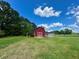 Quaint red barn with white accents, surrounded by a vast green lawn and mature trees at 238 Marks Rd, Mansfield, GA 30055