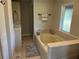 Neutral bathroom with a soaking tub, natural light, and tiled floors at 238 Marks Rd, Mansfield, GA 30055