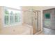 Bright bathroom showcases a glass shower, soaking tub, and views of the outdoors through shuttered windows at 410 Hendon Rd, Woodstock, GA 30188