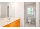 Bright bathroom featuring warm wood cabinets, a marble countertop and tile floor, plus a window over the toilet at 410 Hendon Rd, Woodstock, GA 30188