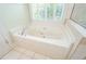 Bright bathroom features a corner jetted tub with a chrome faucet, white tile, and a large window at 410 Hendon Rd, Woodstock, GA 30188
