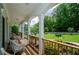 Covered front porch with classic white columns, wooden railings, and wicker furniture, overlooking a well-maintained yard at 410 Hendon Rd, Woodstock, GA 30188
