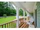 Spacious covered porch enhanced by white columns and rustic wooden railings, offering views of the lush, green landscape at 410 Hendon Rd, Woodstock, GA 30188