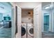 Open laundry closet with washer, dryer, shelving and views into other rooms at 10900 Wittenridge Dr # C7, Alpharetta, GA 30022