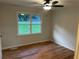 This bedroom features a ceiling fan, and a window providing natural light to the beautiful laminated wood floor at 1321 Earle Se Ct, Conyers, GA 30013