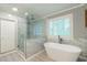 Modern bathroom with a walk-in shower, bathtub, and natural light at 3394 Floral Ct, Suwanee, GA 30024