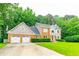 Beautiful two-story home featuring a three-car garage and a lush green lawn with mature trees at 3394 Floral Ct, Suwanee, GA 30024