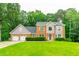 Charming two-story brick home featuring a three-car garage and a well-manicured lawn with mature trees at 3394 Floral Ct, Suwanee, GA 30024