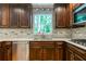 Close-up of kitchen area with wood cabinets, stainless steel appliances, tile backsplash, and bright natural light at 3394 Floral Ct, Suwanee, GA 30024