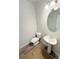 Elegant half bath with a pedestal sink, modern lighting, and sleek gray flooring at 5518 Legacy Trl, Douglasville, GA 30135