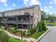 Beautiful brick townhouse with a covered porch, landscaped yard, and a sidewalk on a sunny day at 6460 Cortland Walk, Alpharetta, GA 30005