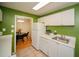 A well lit kitchen shows white appliances and cabinets with green walls and a view into the dining area at 1207 Summit North Ne Dr # 1207, Atlanta, GA 30324