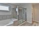 Well-lit bathroom featuring a soaking tub and glass-enclosed shower with bench at 1891 Primrose Park Rd, Sugar Hill, GA 30518