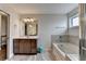 Well-lit bathroom featuring a soaking tub, vanity with dark cabinets, and gray floors at 1891 Primrose Park Rd, Sugar Hill, GA 30518