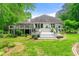 Home's back exterior featuring an expansive porch/deck that overlooks a sprawling lawn and lush landscaping at 312 Crabapple Springs Way, Woodstock, GA 30188