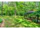 Landscaped backyard with lush lawn, wooded area, stone-lined flower beds, and covered gazebo at 312 Crabapple Springs Way, Woodstock, GA 30188