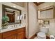 Powder room featuring a wooden vanity, framed mirror, patterned wallpaper, and white fixtures at 312 Crabapple Springs Way, Woodstock, GA 30188