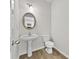 Elegant powder room featuring a pedestal sink, wood flooring, and a round decorative mirror at 3340 Ivey Rdg, Buford, GA 30519