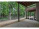 Spacious covered patio with wood columns overlooking a wooded yard and view of the elevated deck above at 541 Lantern Wood Dr, Scottdale, GA 30079