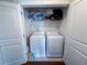 Laundry closet contains side-by-side white washer and dryer units with stacked storage shelf at 82 Auburn Run Ln, Auburn, GA 30011