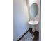 Stylish powder room features an oval mirror, pedestal sink, wood-look flooring, and gray patterned rug at 82 Auburn Run Ln, Auburn, GA 30011