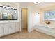 Beautiful bathroom featuring a large mirror, white cabinets, and a tiled floor and tub at 2280 Wildwood Lake Dr, Suwanee, GA 30024